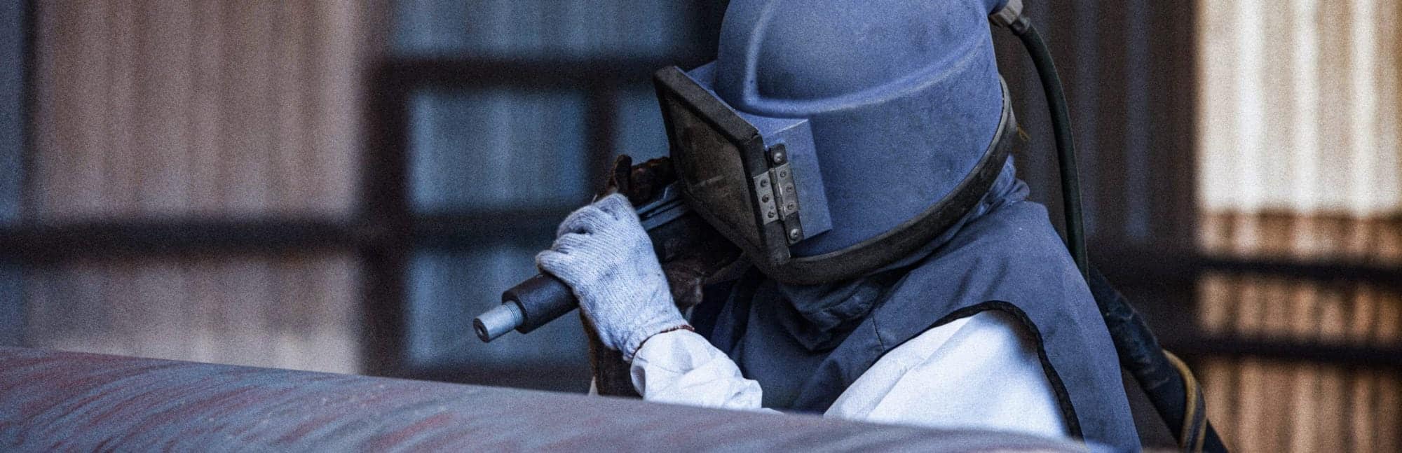 10X-hero-about person sandblasting piece of metal
