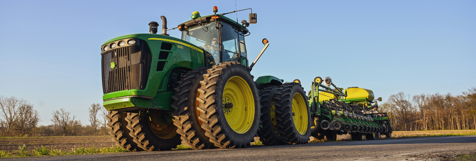 A farmer drives a John Deere tractor with farm machinery on his fields