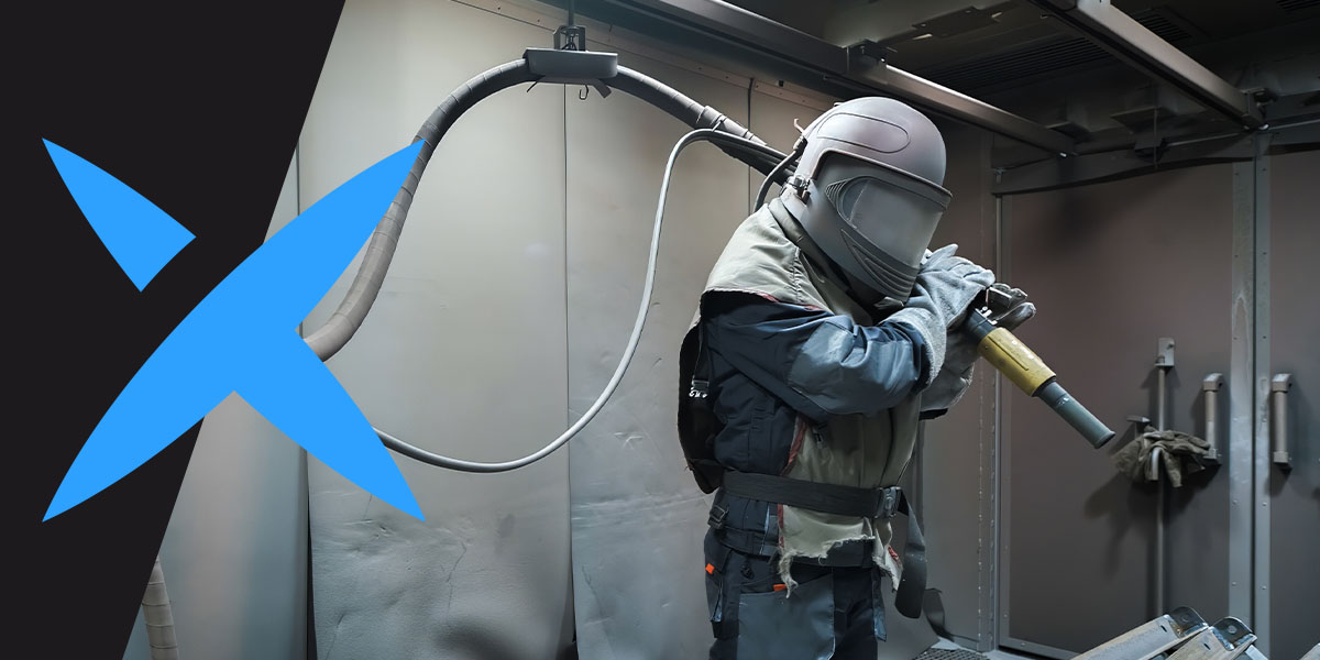 A sandblaster wears PPE while in a blasting room