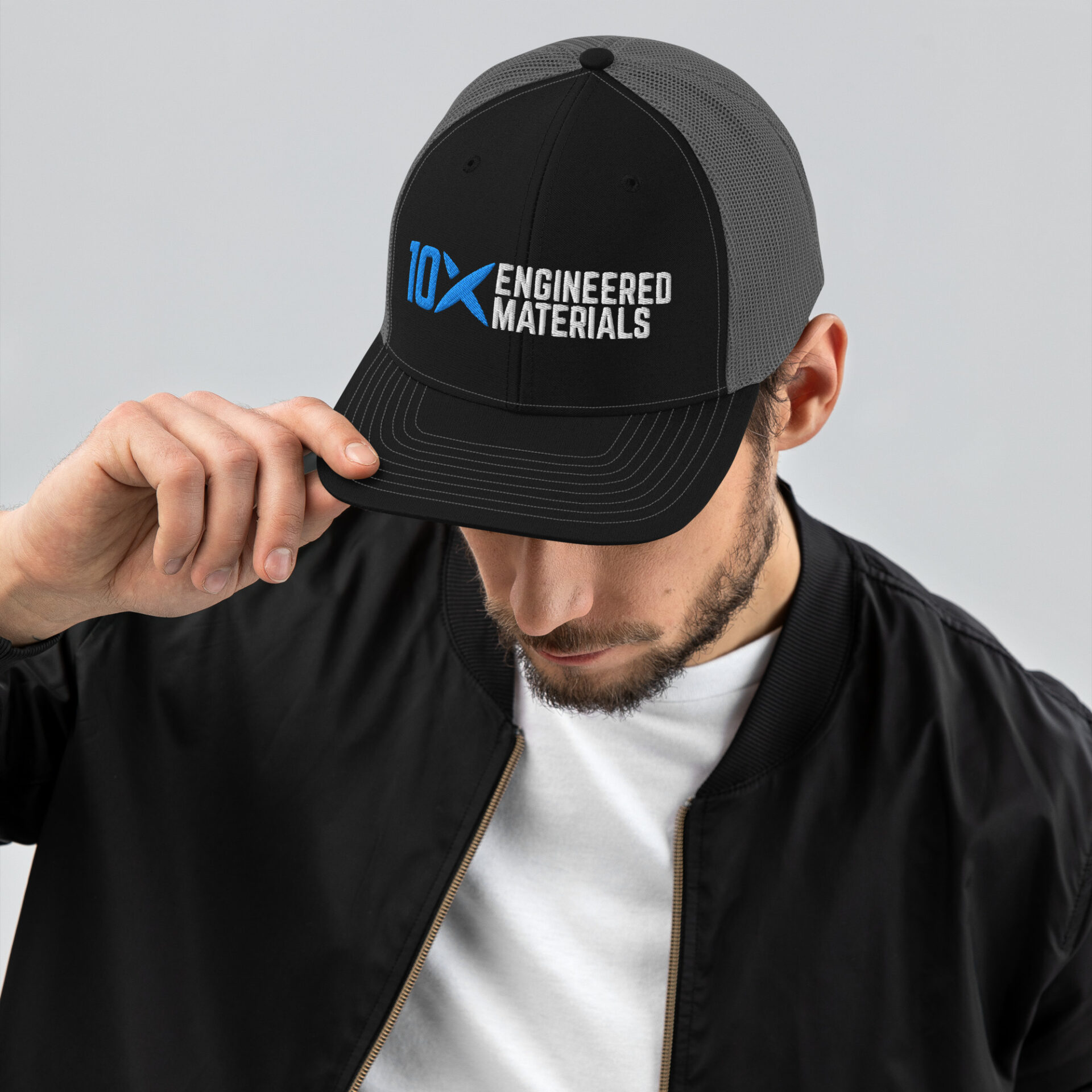 a man wearing a black and grey hat with the 10X Engineered Materials logo on it