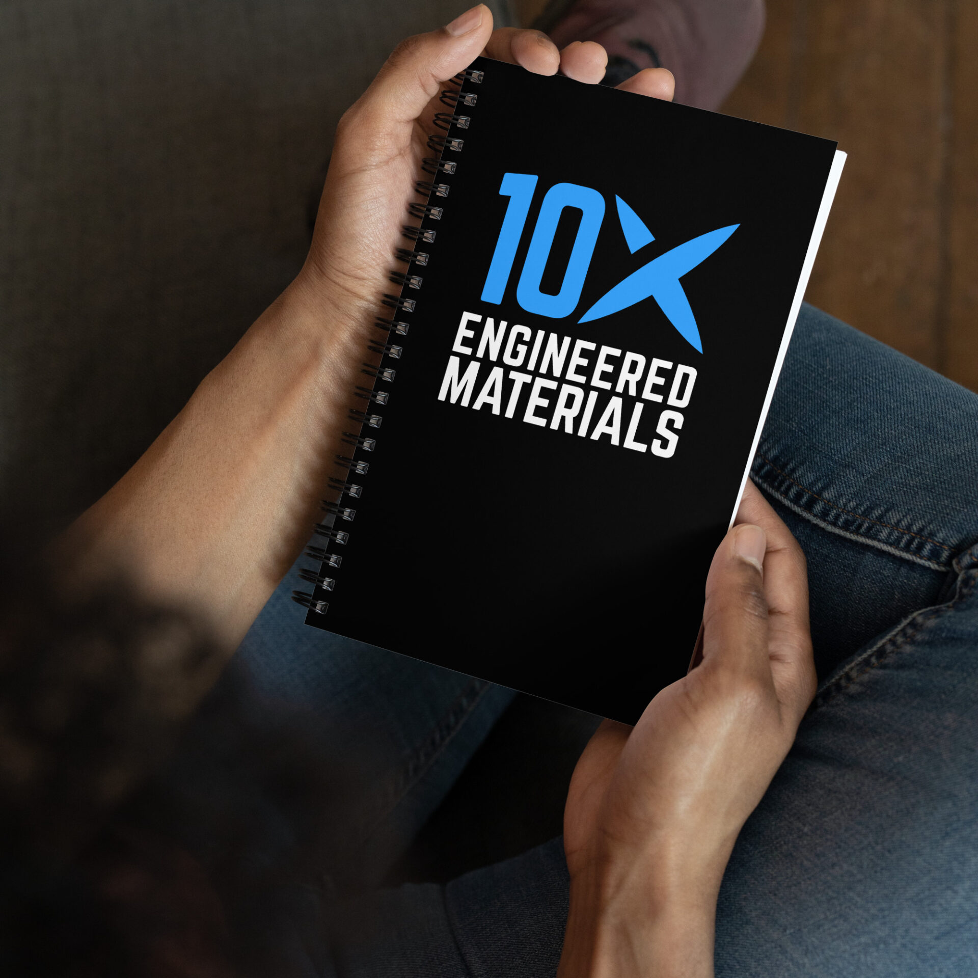 a person is holding a notebook that says 10X Engineered Materials