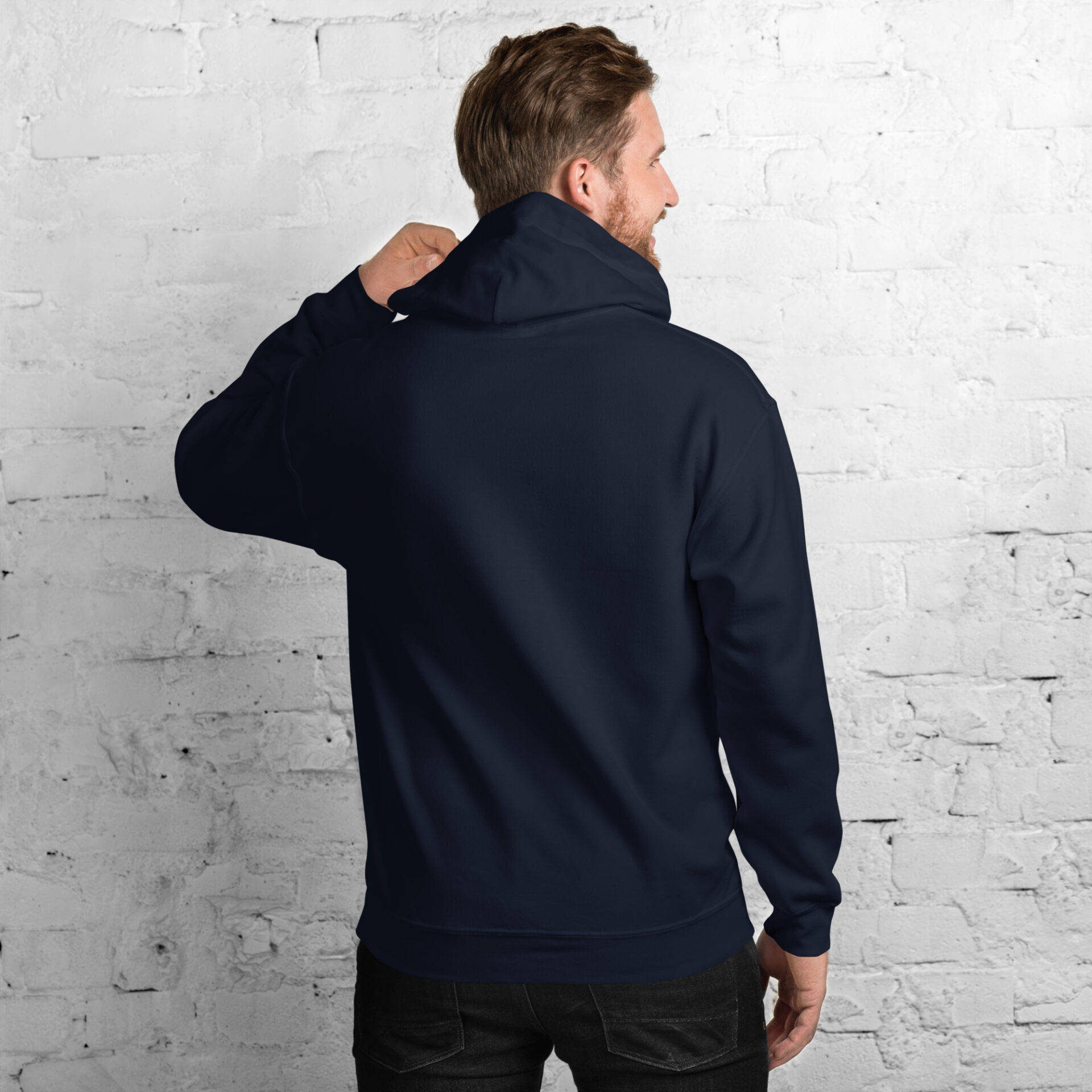 a man wearing a blue hoodie is standing in front of a white brick wall